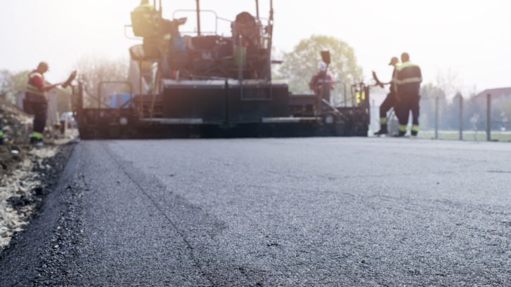 Workers Placing New Coating Of Asphalt On The Road.